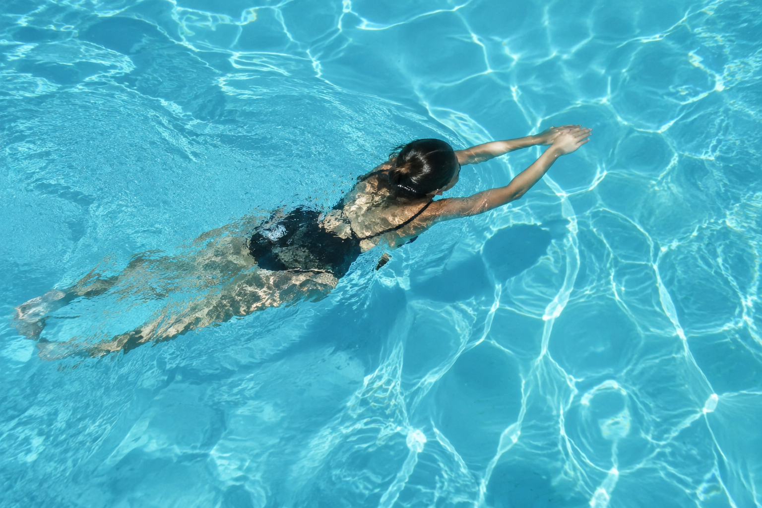 Personne nageant dans une piscine à l'eau claire.